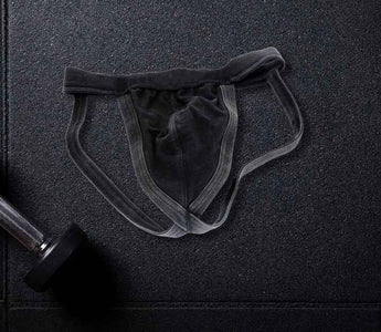 A jockstrap gym supporter lays on a gym floor