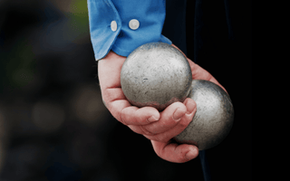 A man holds silver balls in his hand