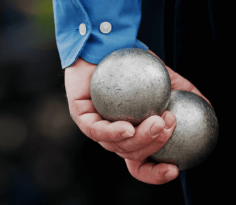 A man holds silver balls in his hand