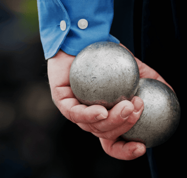 A man holds silver balls in his hand