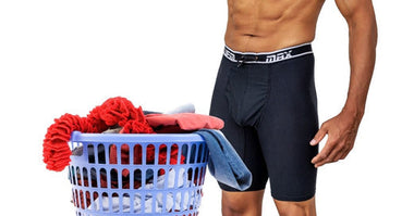 A man wears black UFM extra long boxer briefs while doing laundry